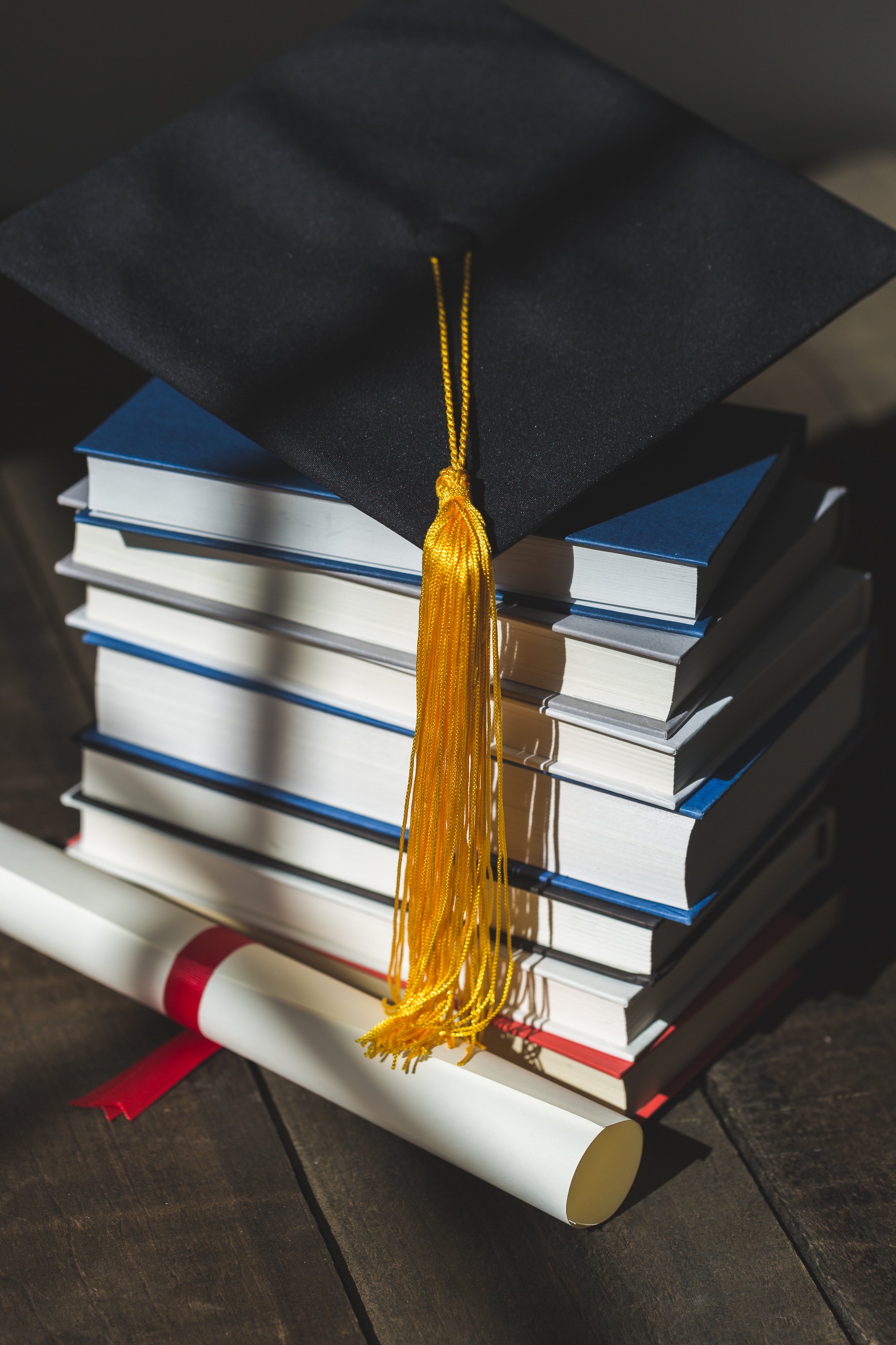 Grad cap on books with a diploma
